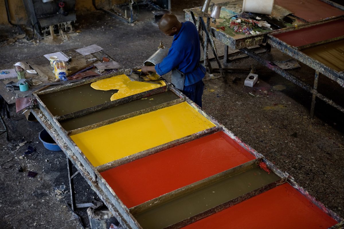 Swazi Candles artisan cutting layered sheets of dyed wax by hand during the millefiore process
